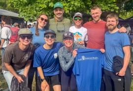 Grupo de ocho personas posa junto mientras sostiene una camiseta azul de Skagit Regional Health.