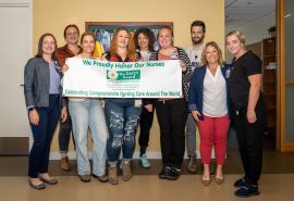 Micaela y equipo sostienen el cartel del premio DAISY Award