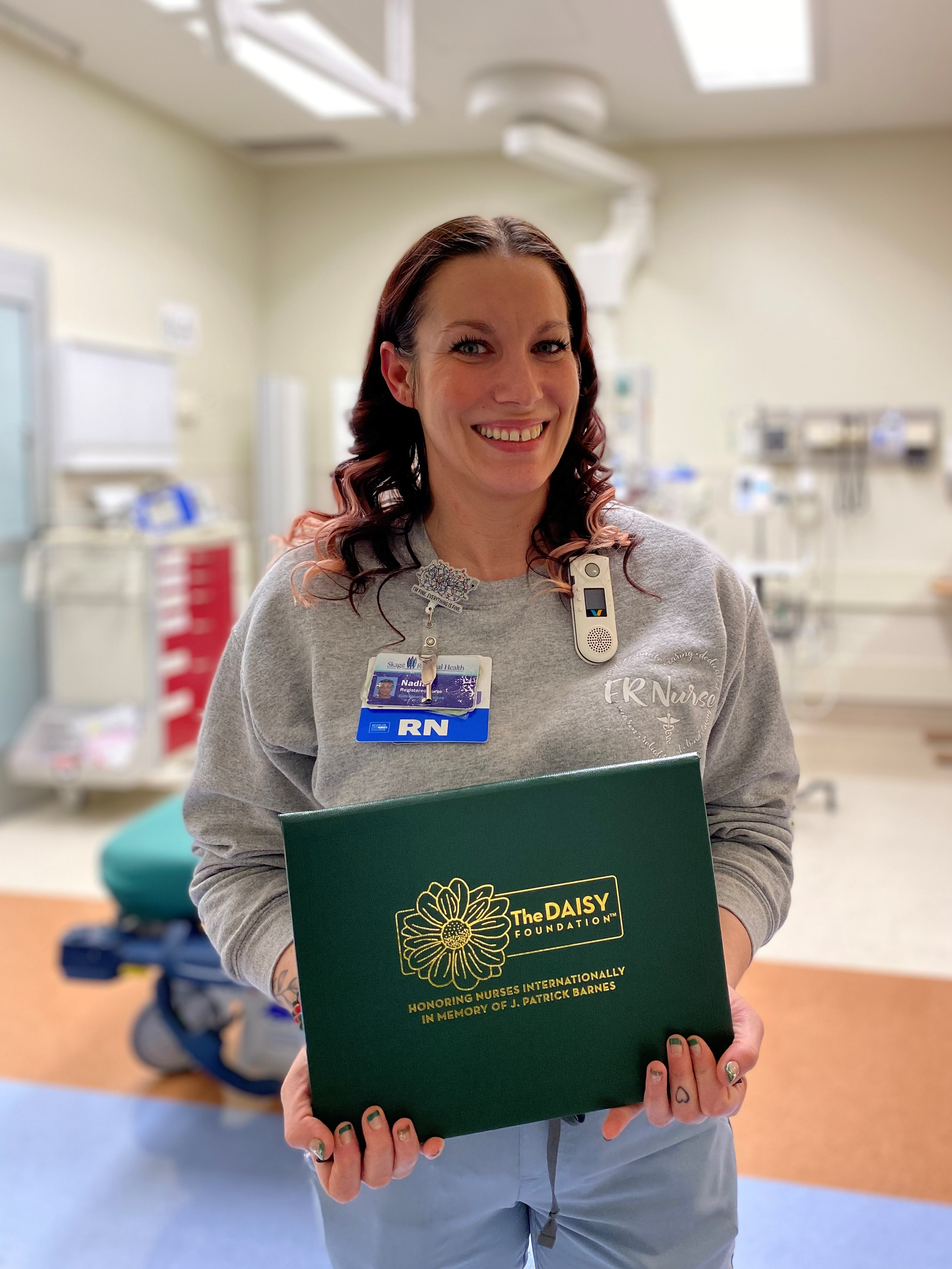 Nadia Nicholson, enfermera registrada, sostiene su certificado del premio DAISY