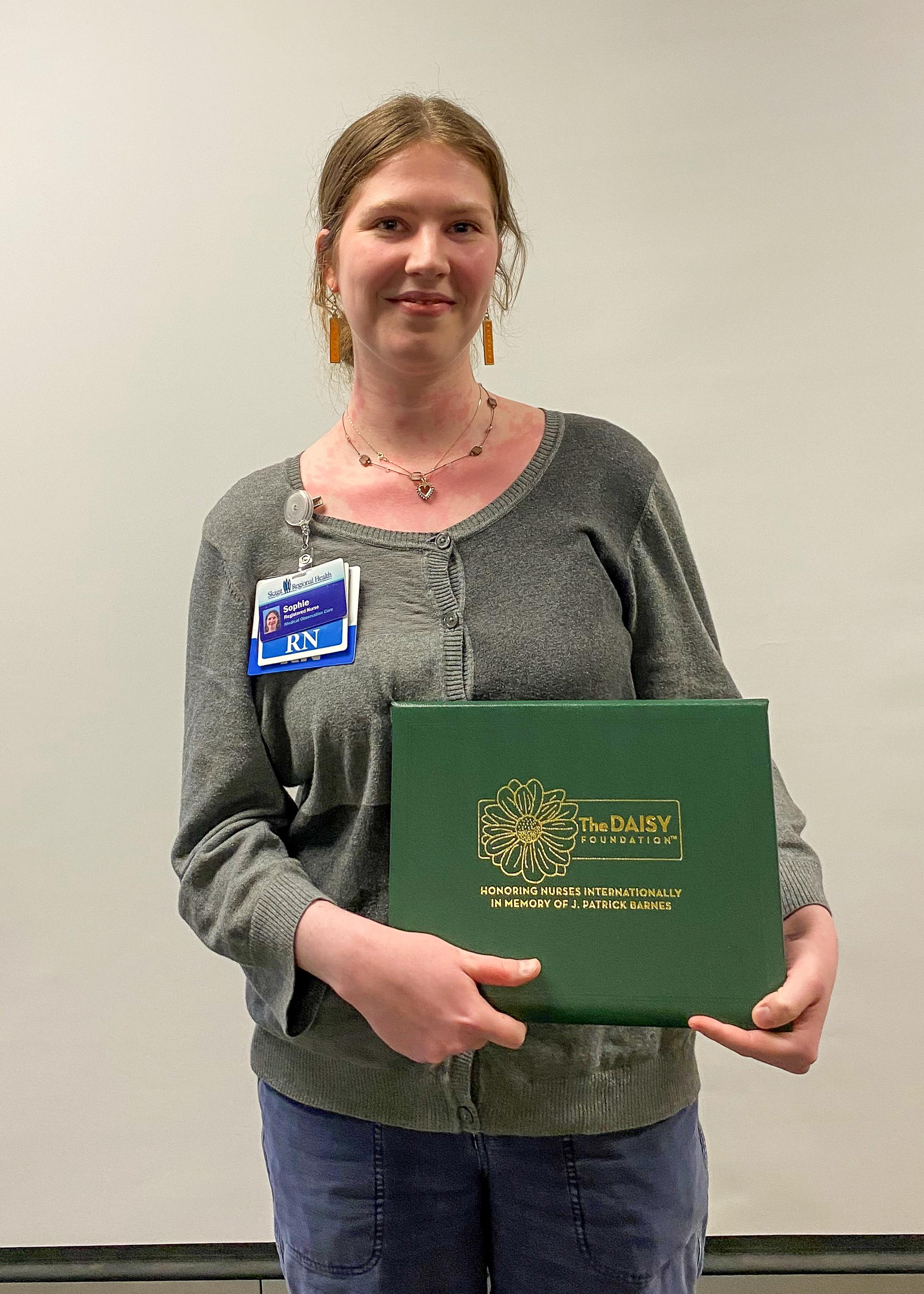 Sophie Porterfield, RN, sostiene el certificado de su DAISY Award.