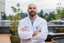 Dr. James Barger stands outside wearing a white coat and has arms crossed.