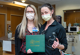 Dos enfermeras de SVH posan con su certificado del premio DAISY Award y la escultura Healer's Touch.