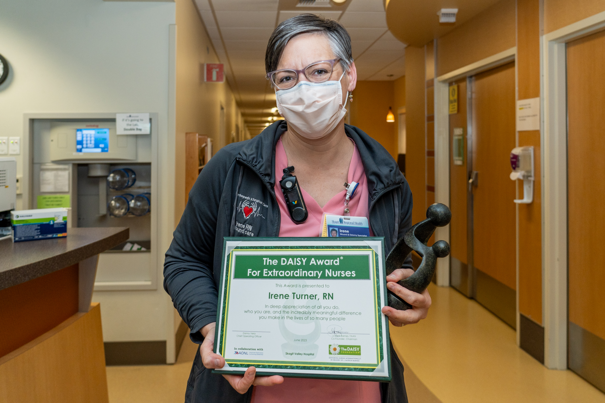 Irene posa con su certificado del premio DAISY Award y la escultura Healer's Touch.