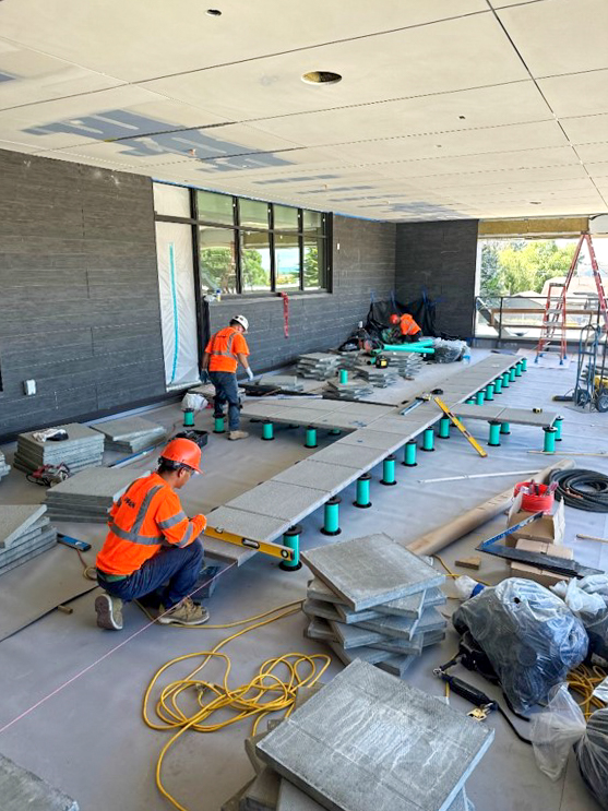 Construction workers install a patio on an outdoor deck.
