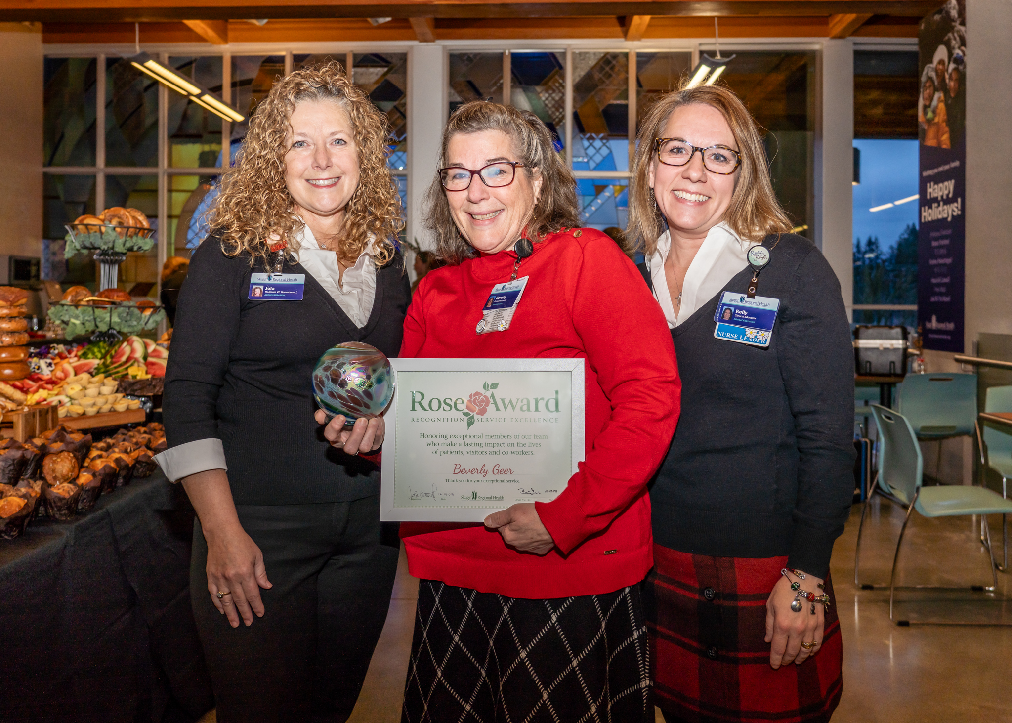 Beverly pictured in middle between two other women. Beverly holds Rose Award and certificate.