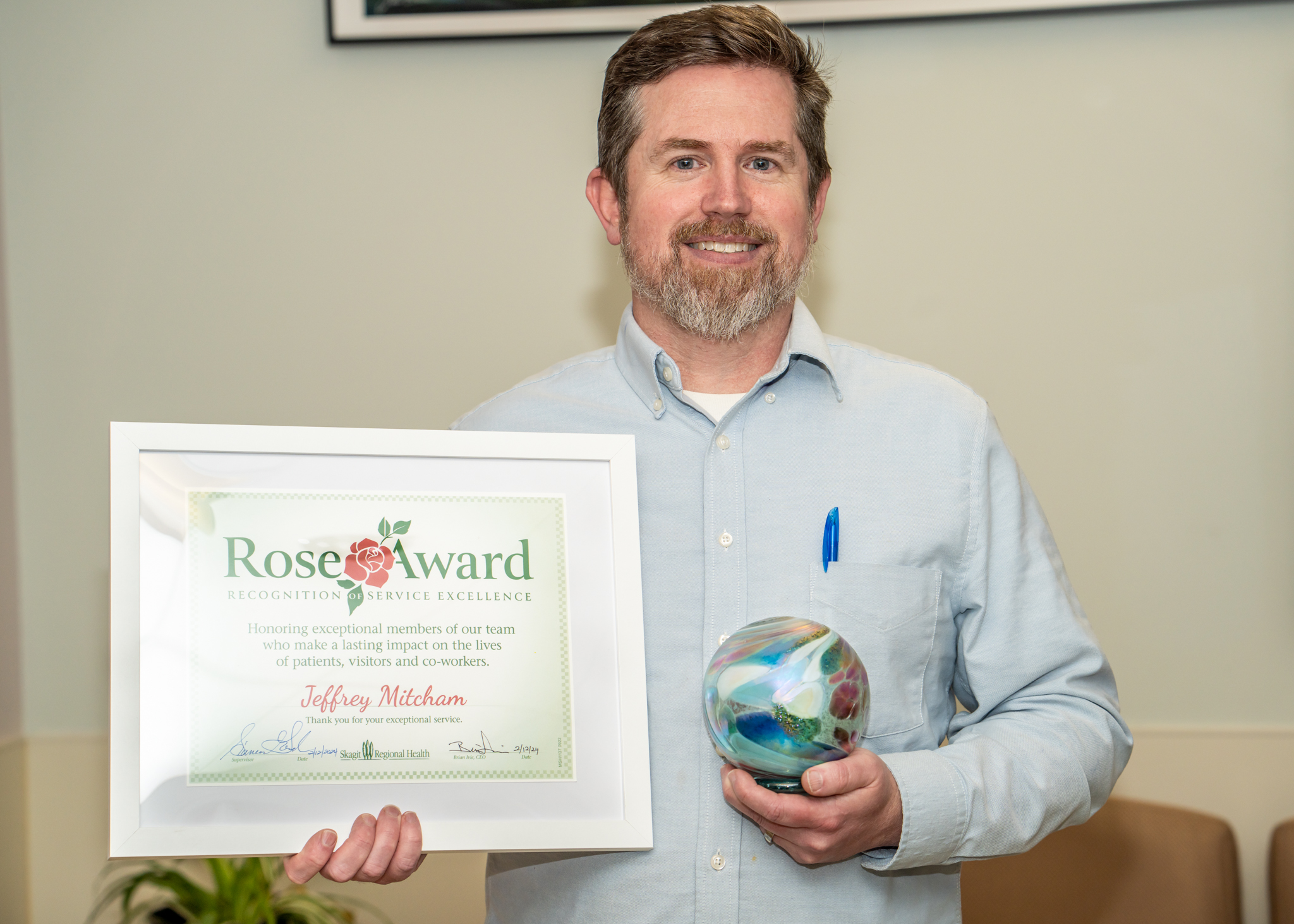 Jeffrey Mitcham sostiene el certificado y el premio Rose Award.