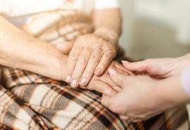 Persona anciana y joven sosteniéndose las manos: concepto de atención para ancianos