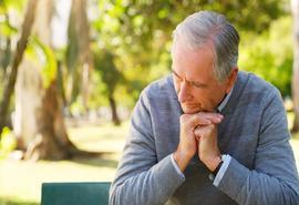 Depression, thinking and senior man in garden sitting on bench for fresh air in nature.