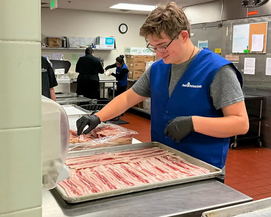 Rowan Hiller, estudiante del ATTIC, prepara una bandeja de tocino.