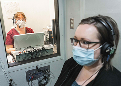 Audiologist performs hearing test on patient.