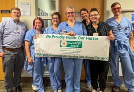 Group of healthcare workers with DAISY Award winner holding DAISY Award banner.
