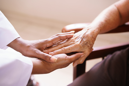 Geriatric patient holds female doctor's hand