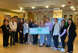 Grupo de personal de enfermería en la unidad hospitalaria sonríen con la ganadora del premio