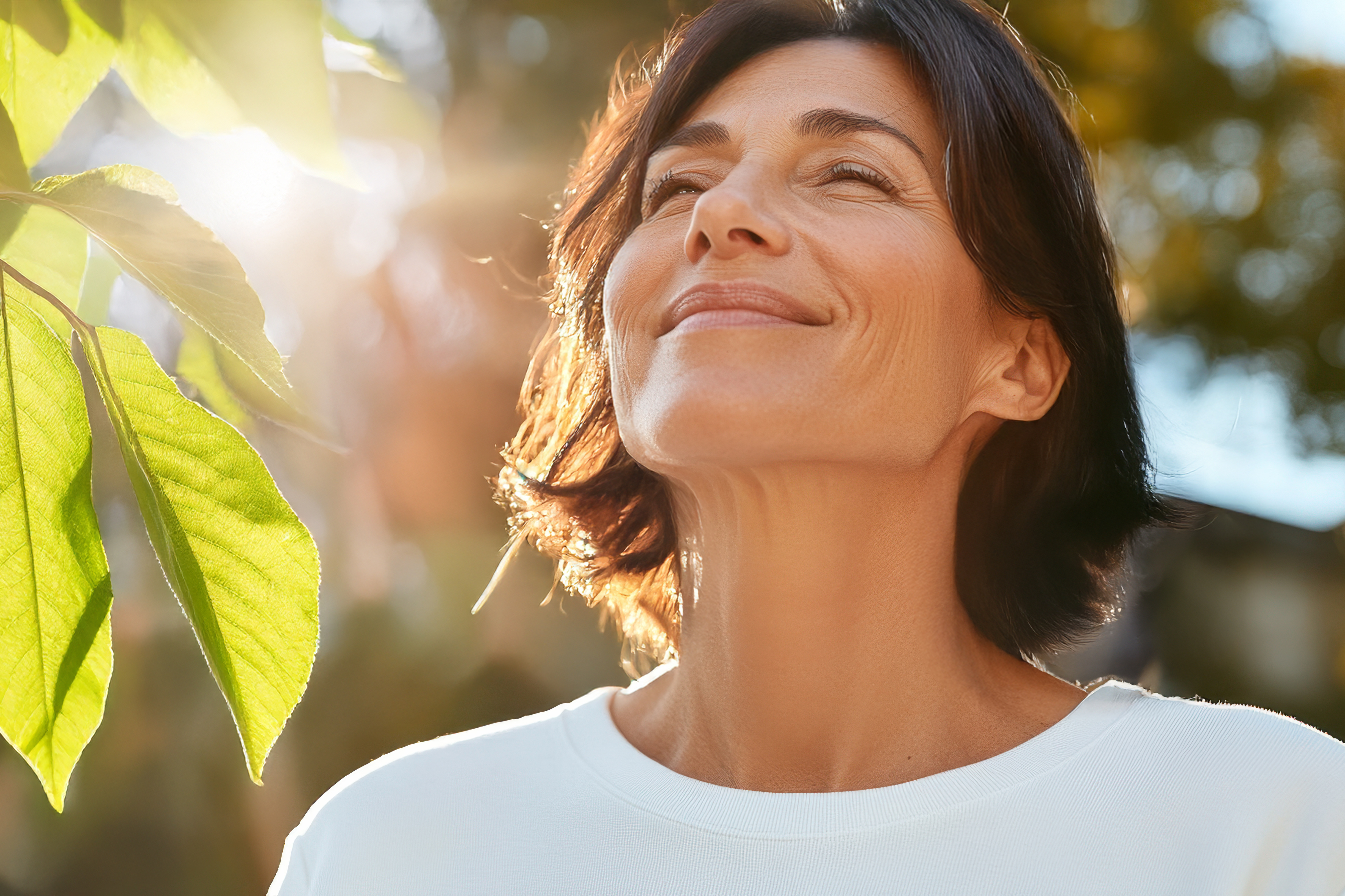 Woman standing in sun near leaves