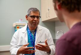 Un médico habla con un paciente en una sala de examen