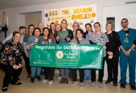 El equipo de enfermería sostiene un cartel en honor a un miembro reconocido con el premio DAISY