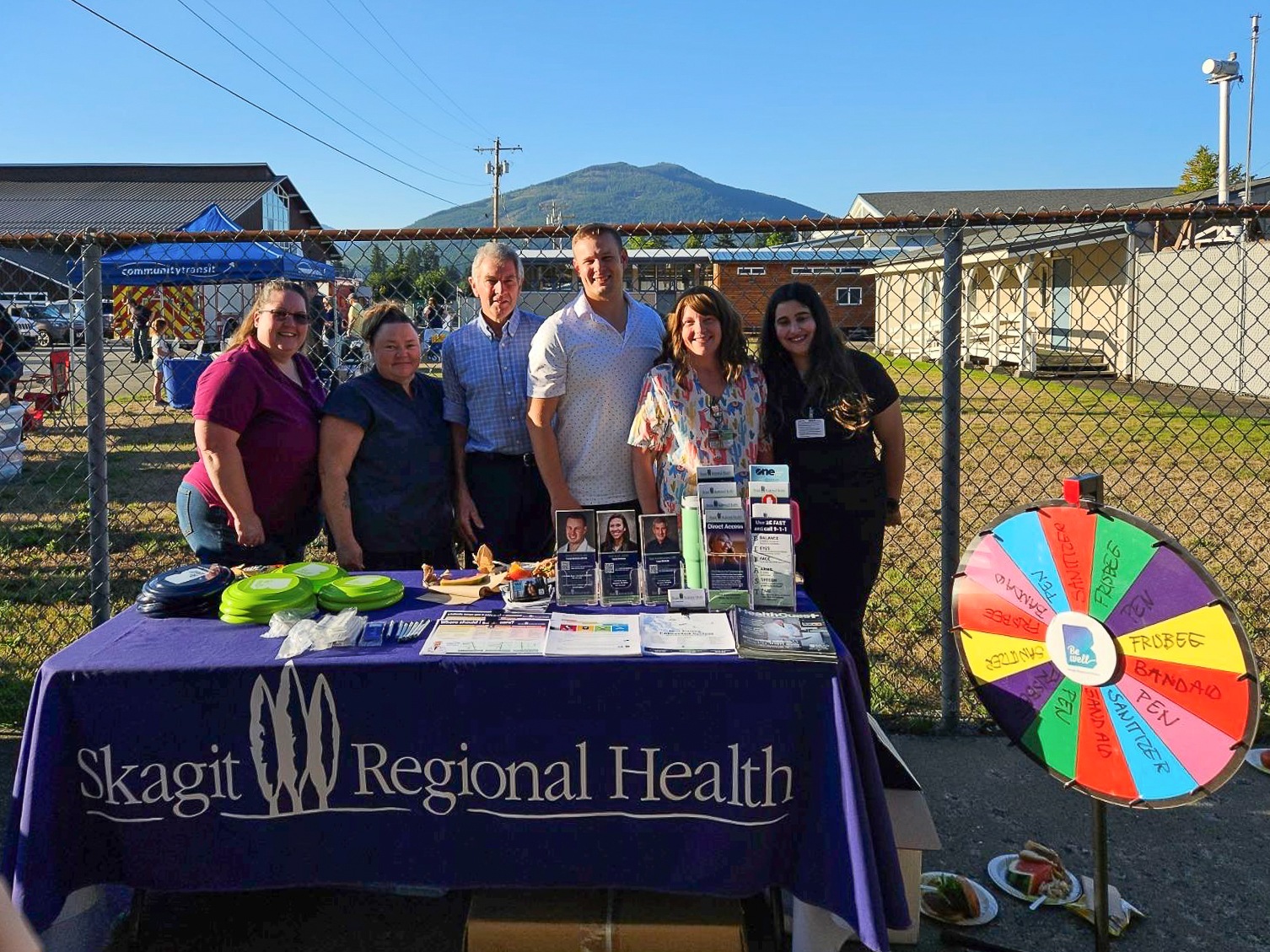Darrington clinic staff and providers stand behind SRH table with a spinning prize wheel to the right of them.
