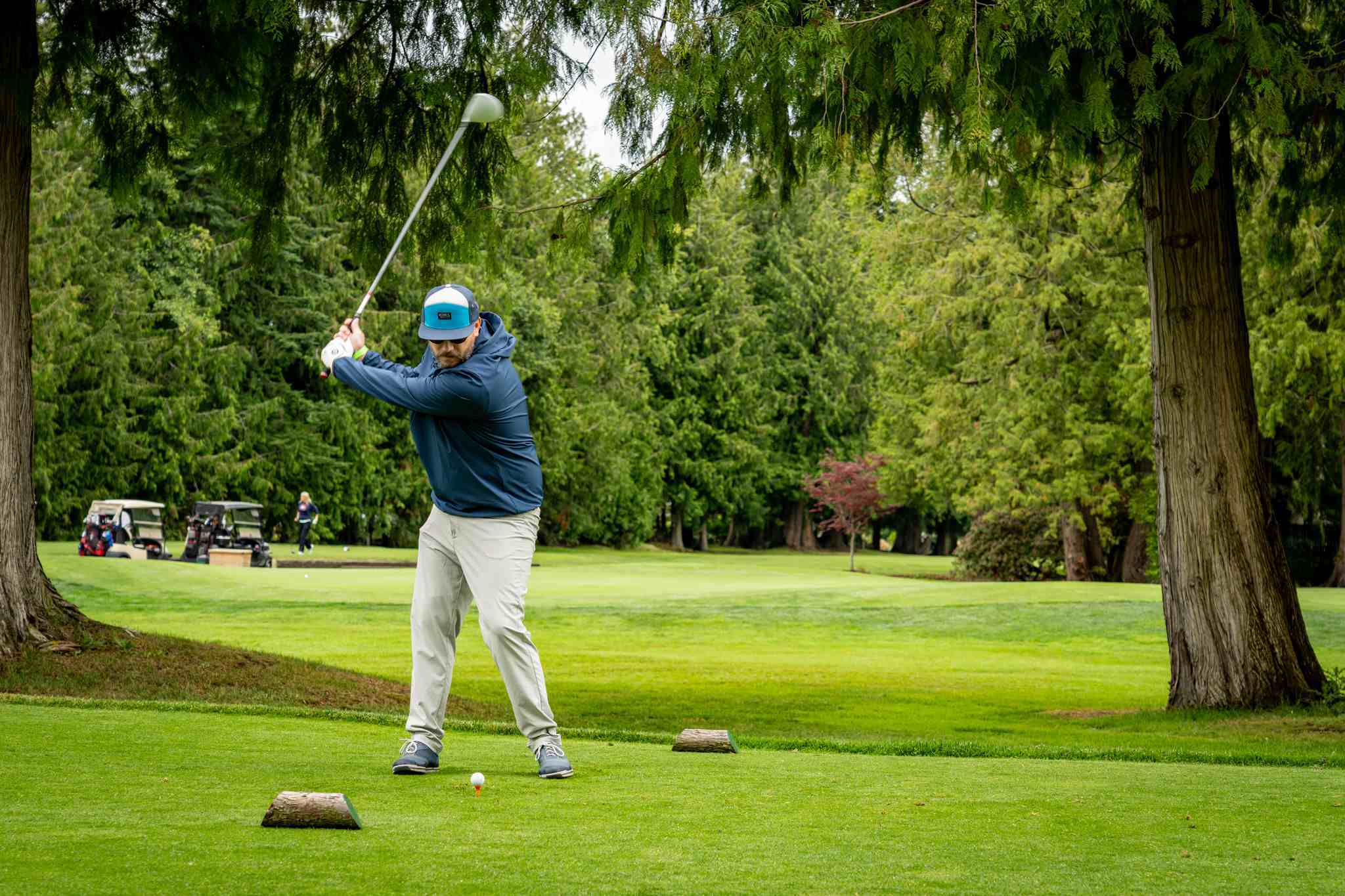 Hombre balanceando su palo de golf en el tee de salida en un campo de golf