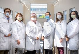 Un grupo de seis médicos residentes posan con batas blancas y mascarillas.