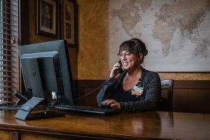 Woman sitting at a desk with a computer talking on the phone.