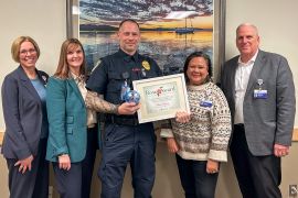 Adam Young sostiene el premio Rose Award y el certificado, posando con ejecutivos de Skagit Regional Health.