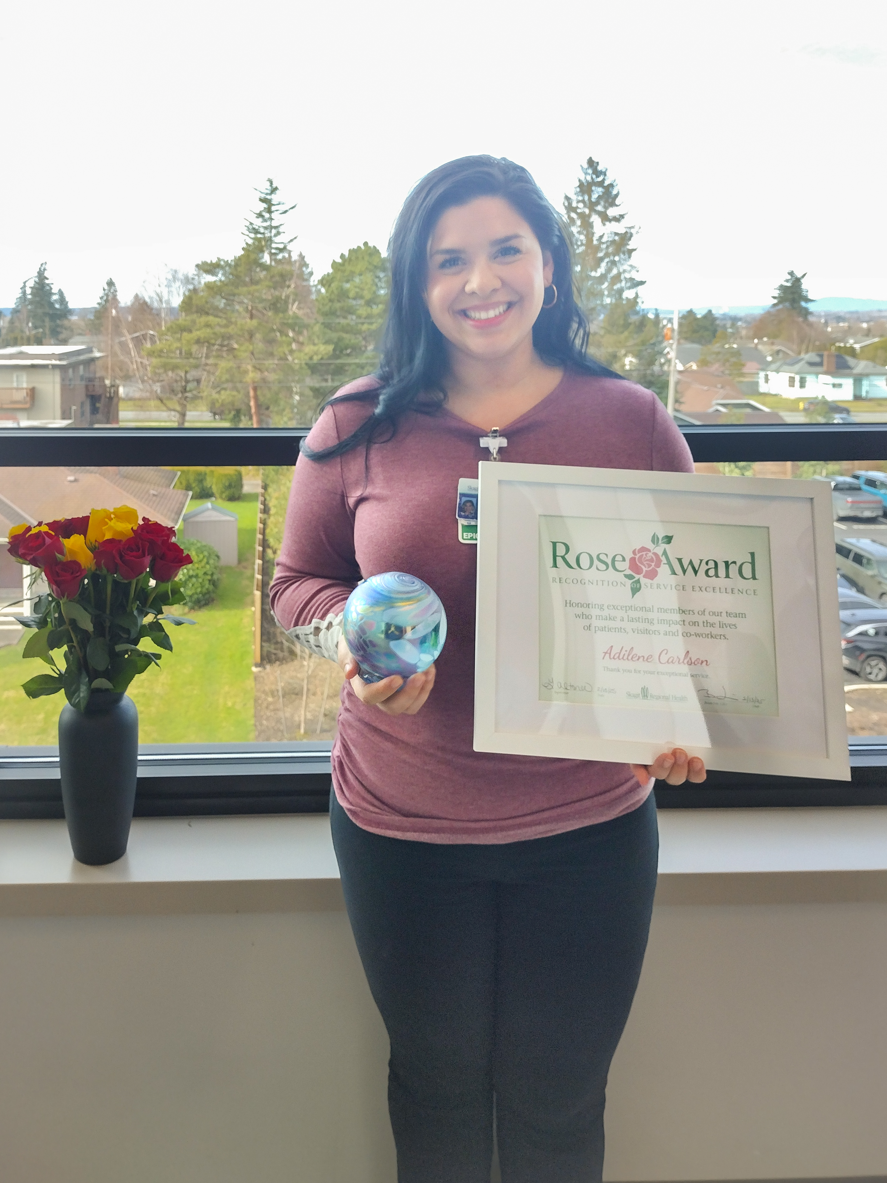 Addie Carlson, ganadora del premio Rose Award de enero 2025, posa con el premio y el certificado.