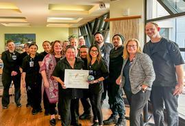 Large group of people gather in public dining area and pose around rose award winner.