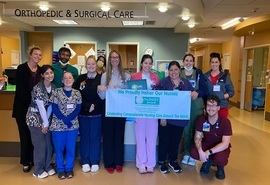 Un grupo de enfermeras sostiene un letrero de ganador del premio DAISY