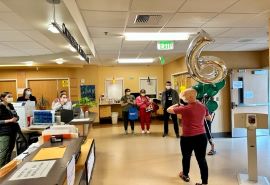 Emily is surrounded by Skagit Valley Hospital staff clapping as she celebrates chemotherapy completion.