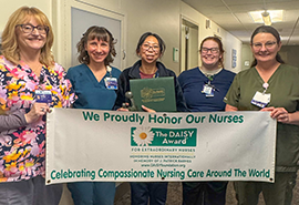 A group of nurses holding a banner for an award recipient