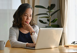 Una mujer sentada a una mesa en su casa usando una computadora portátil