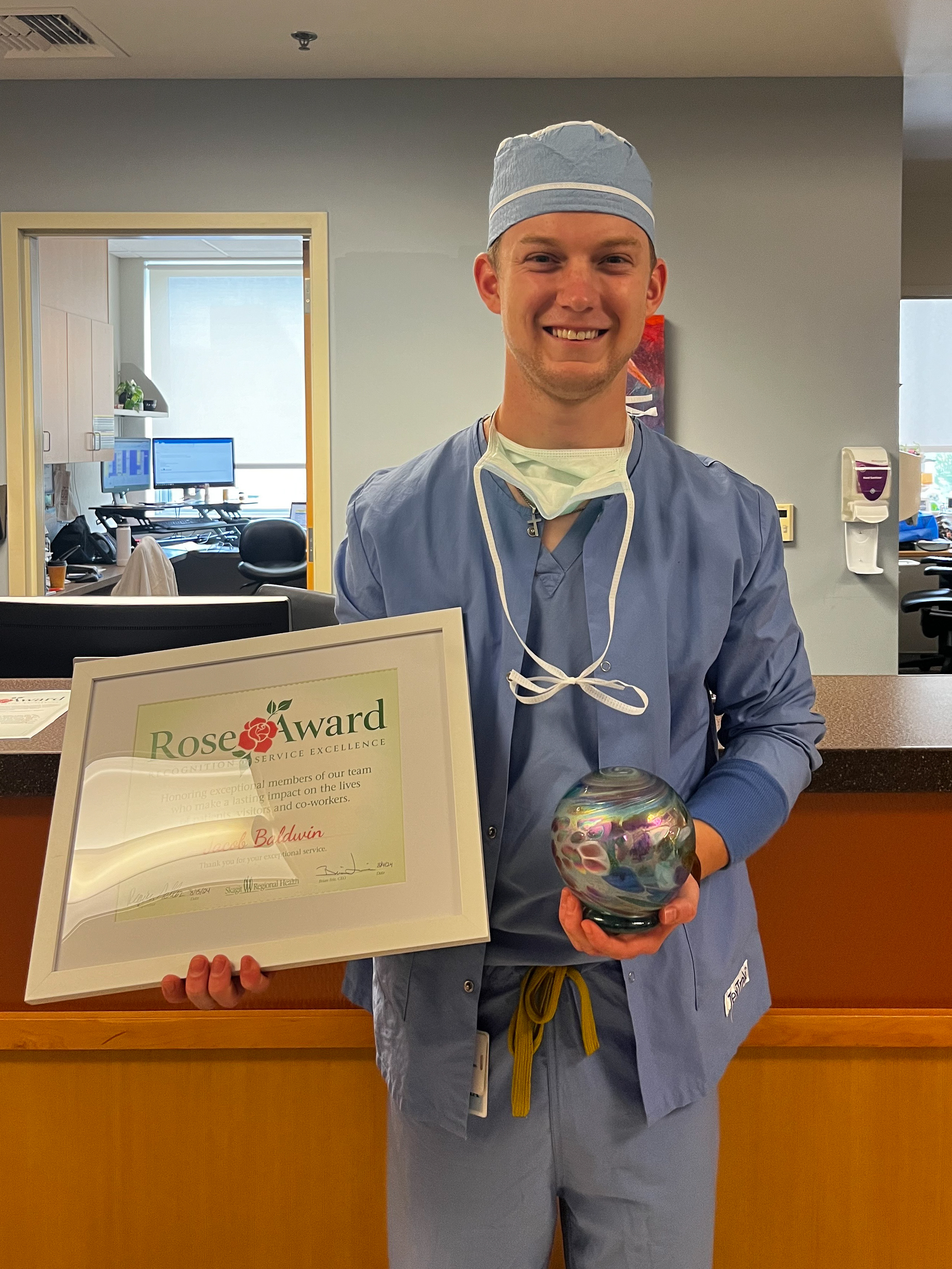 Jacob Baldwin viste ambo azul y sostiene el Rose Award y su certificado.