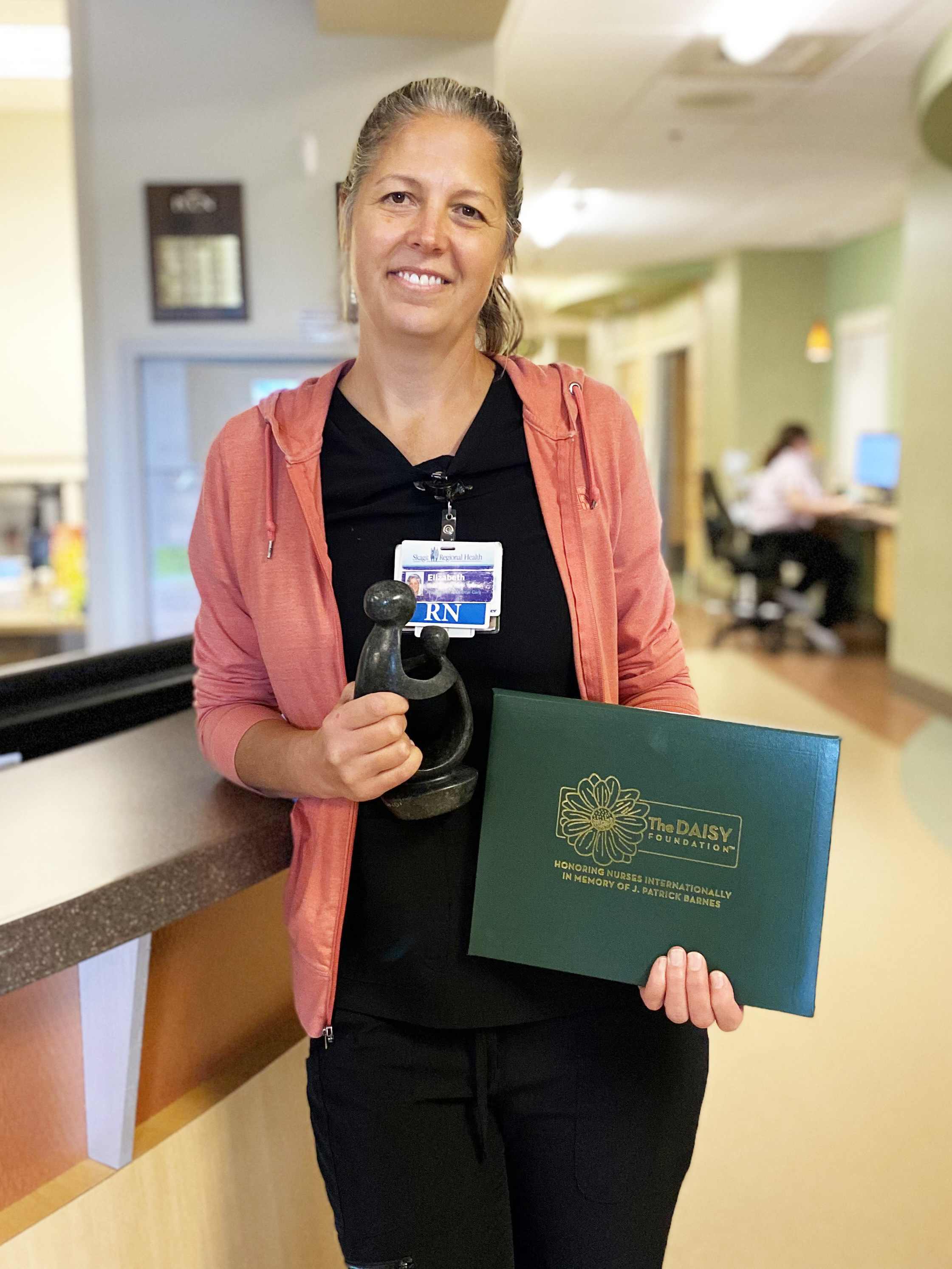 Mujer sosteniendo un premio en la unidad de cuidados hospitalarios