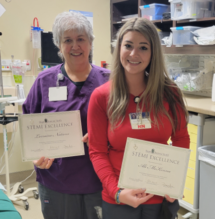 Two women pose with STEMI Excellence certificates. 