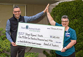 Two adults giving a high five as they pass a donation check