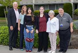 Six people standing together outside of a hospital building in business casual clothing