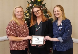 Karla Dills, Sarah Pelle y Michelle O'Bryant posan con la placa Empleador del Año 2024 de WVS.