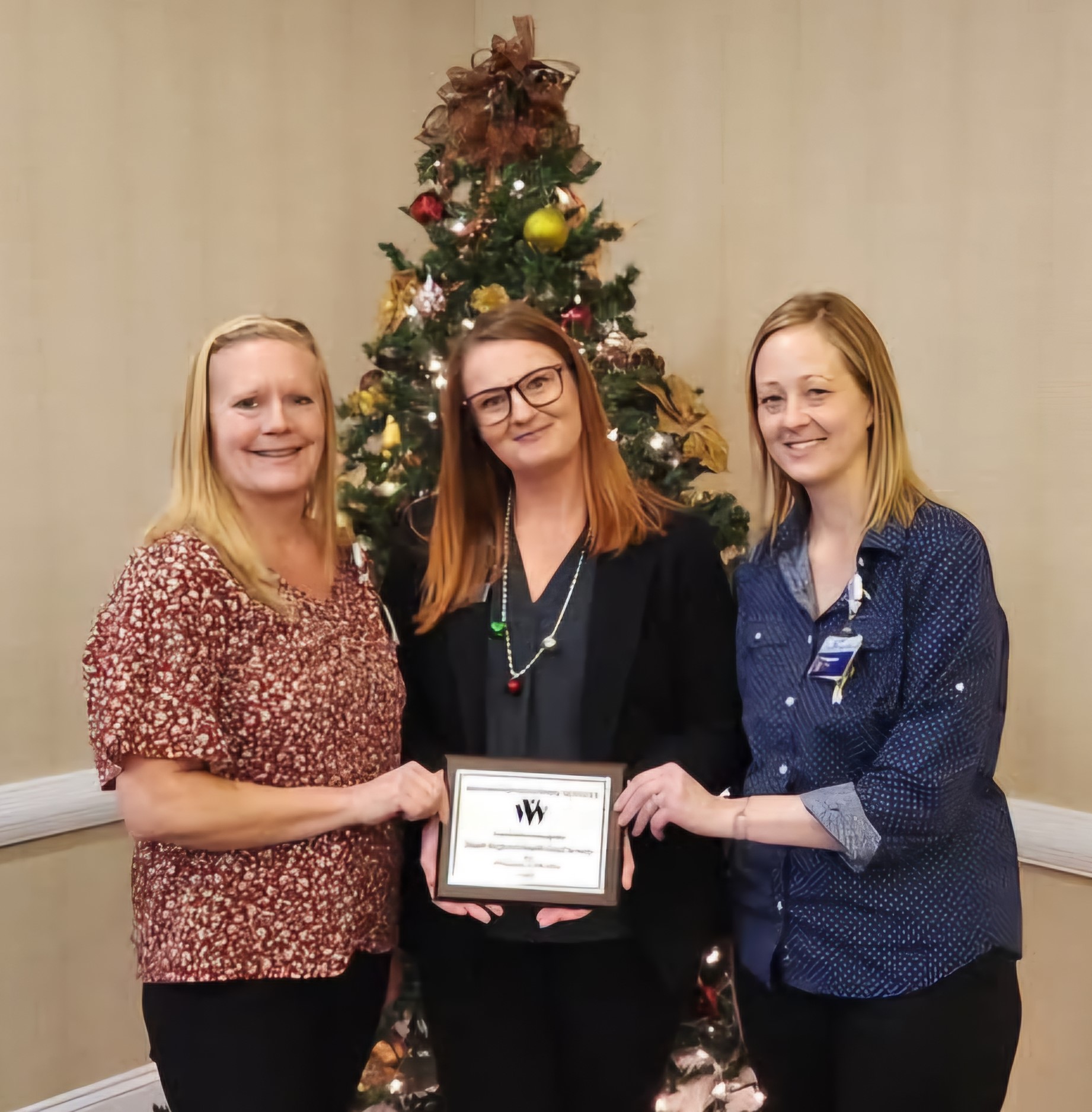 Karla Dills, Sarah Pelle y Michelle O'Bryant posan con la placa Empleador del Año 2024 de WVS.