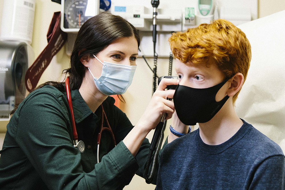 Provider checking youth ear during exam